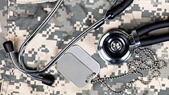 stethoscope and military ID tags on top of camo fatigues