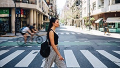 a woman dressed casually walks across a city street